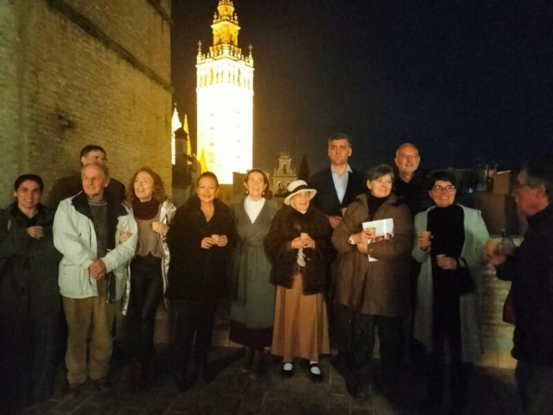 Gruppo di persone in posa di fronte alla Giralda di Siviglia di sera.