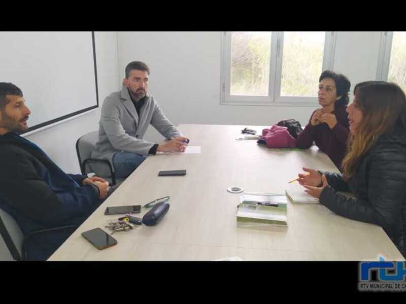Reunión de trabajo en una sala de reuniones con cuatro personas alrededor de una mesa.