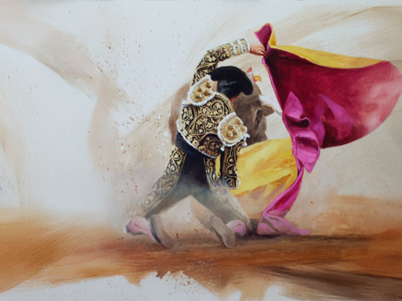 Un torero en acción, con su capa y muleta en movimiento, en un entorno de arena.