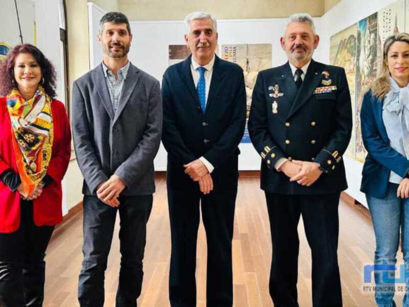 Una reunión formal entre cuatro personas, incluyendo a un oficial militar, en un entorno profesional. La escena sugiere una conversación o presentación de importancia.