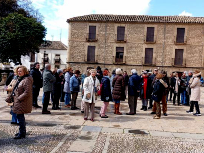 Grupo de personas visitando un edificio histórico en una plaza de pueblo.