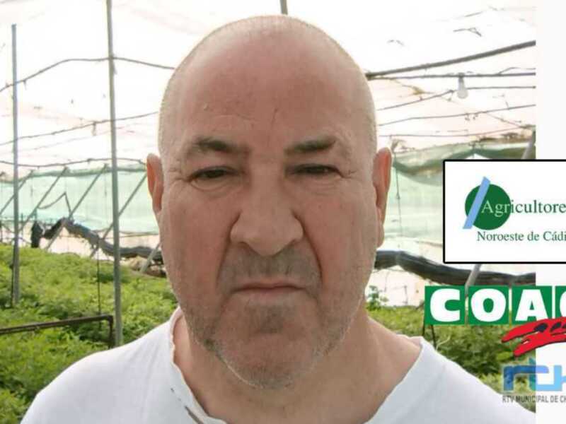 Un hombre con barba y una camiseta blanca, frente a un fondo de vegetación y estructuras de metal. Logotipo de Agricultores Noroeste de Cádiz en la esquina superior derecha. Logotipo de RTM en la esquina inferior derecha.
