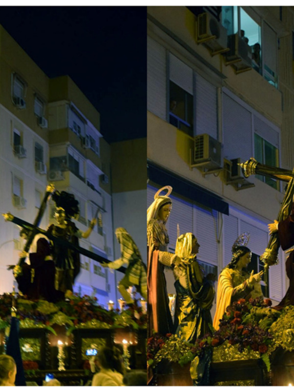 Processión religiosa nocturna con estatuas de santos y crucifijos, en un entorno urbano con edificios y luces de fondo.