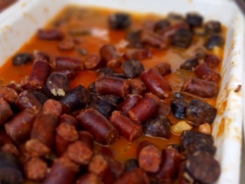 Salsichas y judías en salsa, servidas en bandeja para una cena al aire libre.