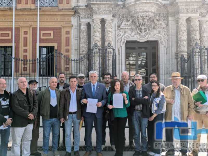 Una reunión de negociación en el exterior de un edificio histórico, con varios individuos sosteniendo papeles y discutiendo.