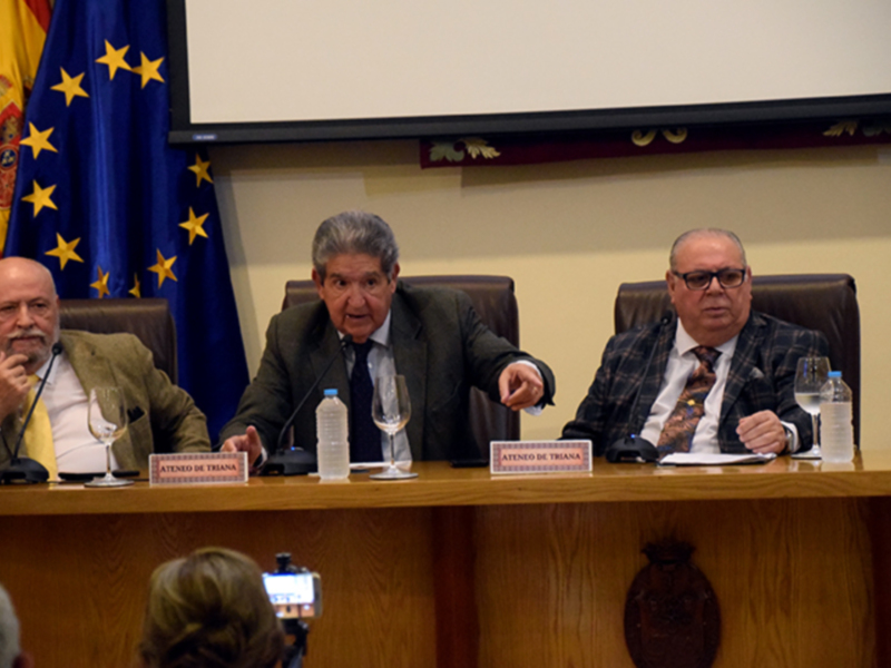 Reunión en el Ateneo de Triana, con banderas españolas y europeas en el fondo.