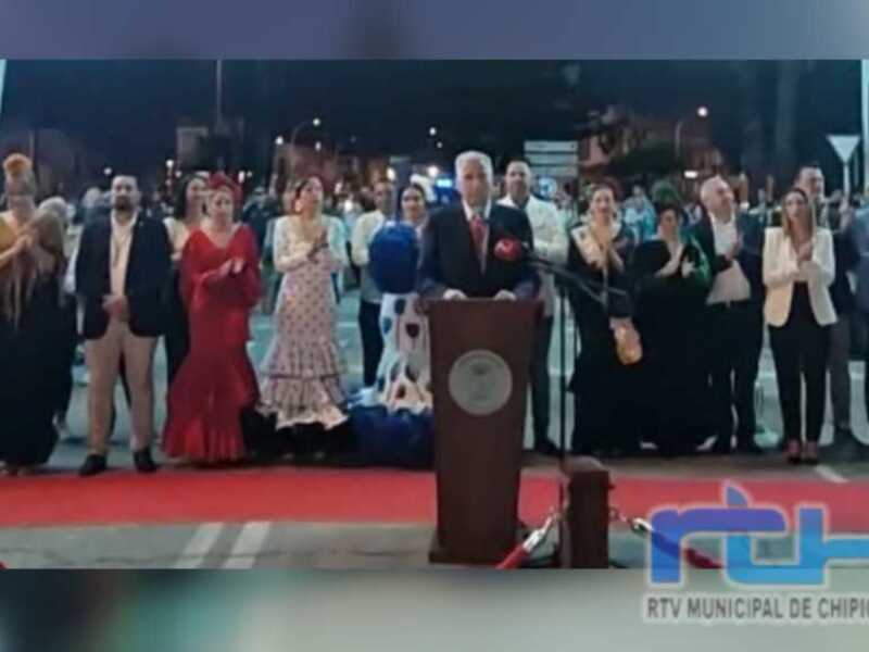 Celebración pública con un discurso en un podio, rodeado por una audiencia en una noche de verano.
