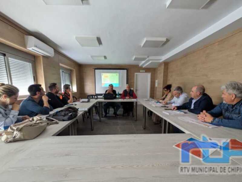 Reunión de trabajo en una sala de conferencias con una presentación en pantalla en el centro.