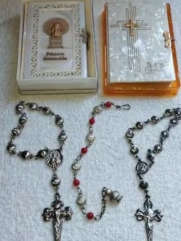 Colección de rosarios y objetos religiosos, incluyendo una imagen de la Virgen María y cruces decorativas.