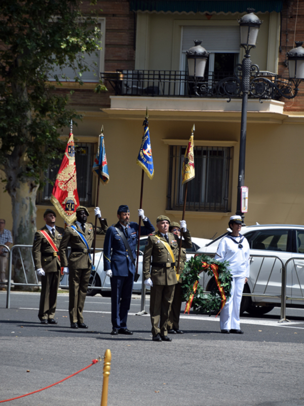 Desfile militar con uniformes y banderas en una calle urbana.