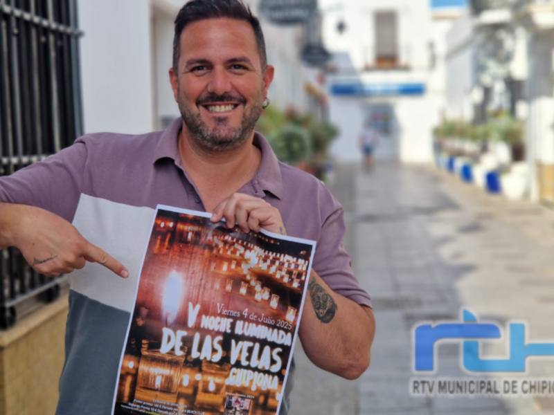 Un hombre sonriente muestra un cartel de la Noche Iluminada de Las Velas en Chipiona, con fecha del viernes 4 de julio de 2025.