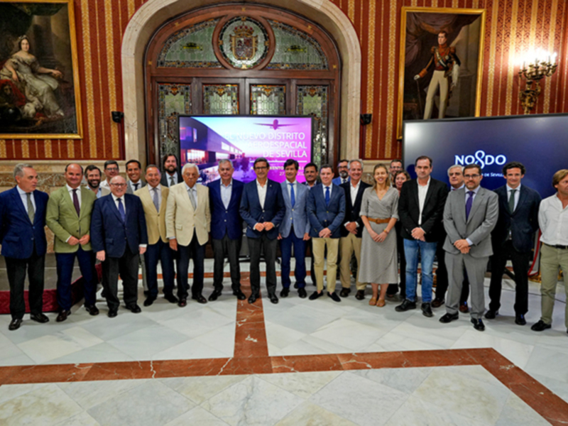 Reunión de empresarios en el Palacio de San Telmo, Sevilla, con el lema 'NOSDO' en el fondo.