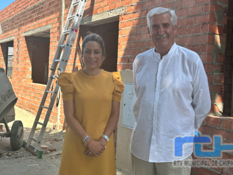 Dos personas sonríen frente a una construcción en fase de construcción.