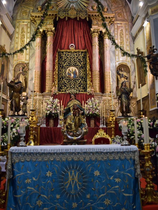 Altar ornado con estatuas, flores y decoración dorada en una iglesia.