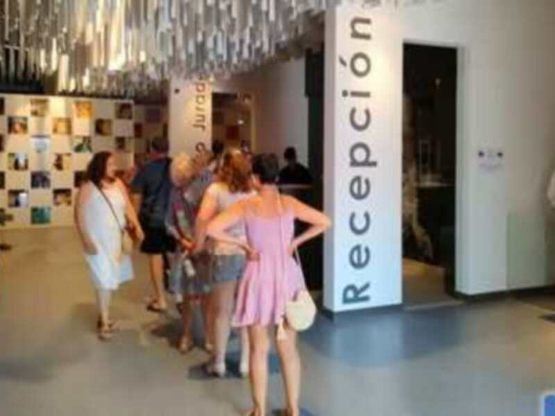 Visita guiada en un museo con recepción en el fondo y visitantes explorando exposiciones.