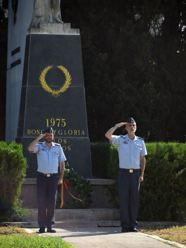 Dos soldados en uniforme militar realizan una salutación militar frente a un monumento con la fecha 1975 y el nombre 'HONOR Y GLORIA'.
