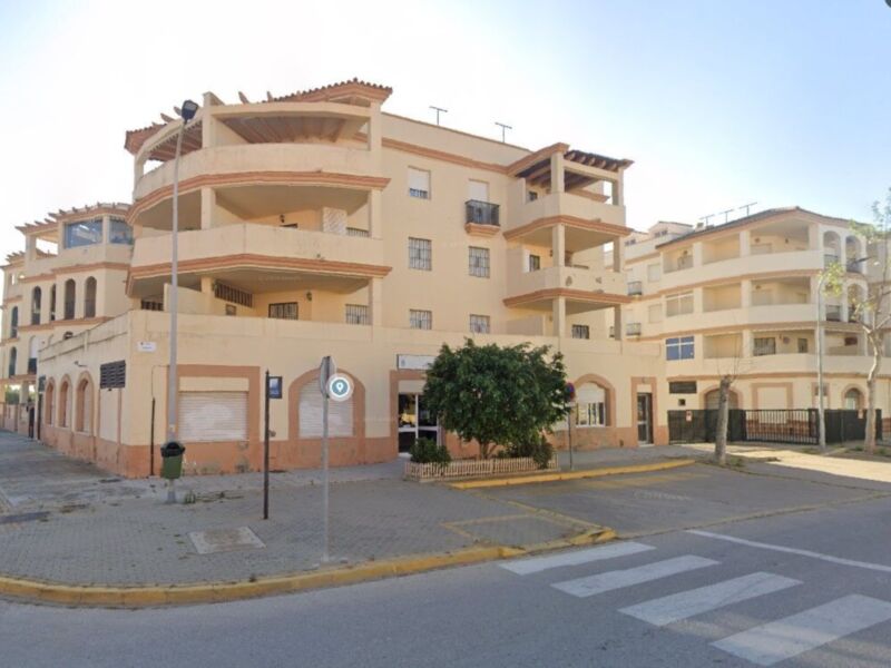 Edificio de apartamentos con balcones y arquitectura mediterránea en un entorno urbano.