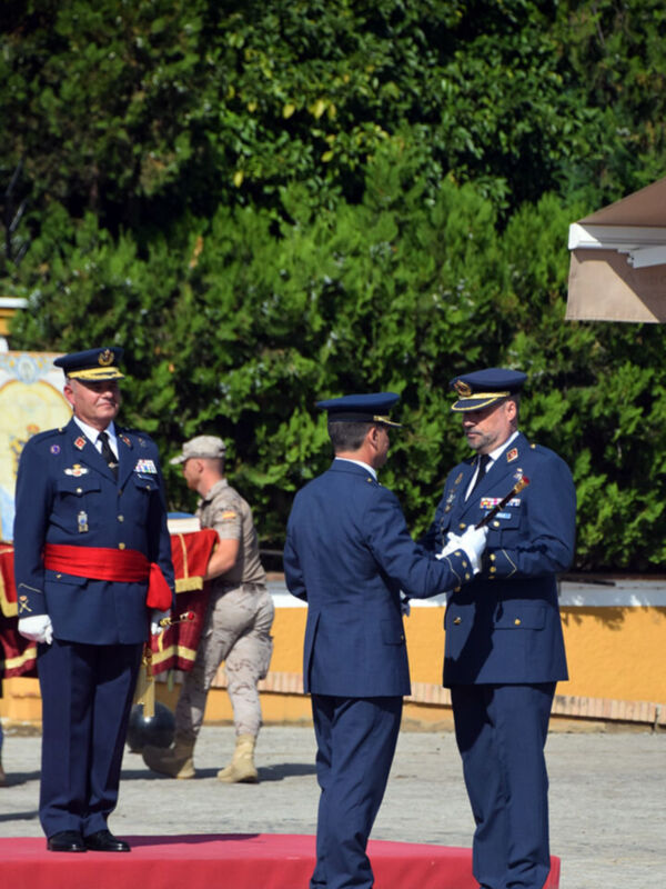 Guardia de honor en una ceremonia militar, con oficiales uniformados en un escenario rojo.