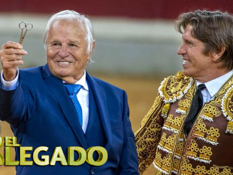 Celebración de la tauromaquia: un hombre en traje y otro en traje de luces sonríen en el ruedo.