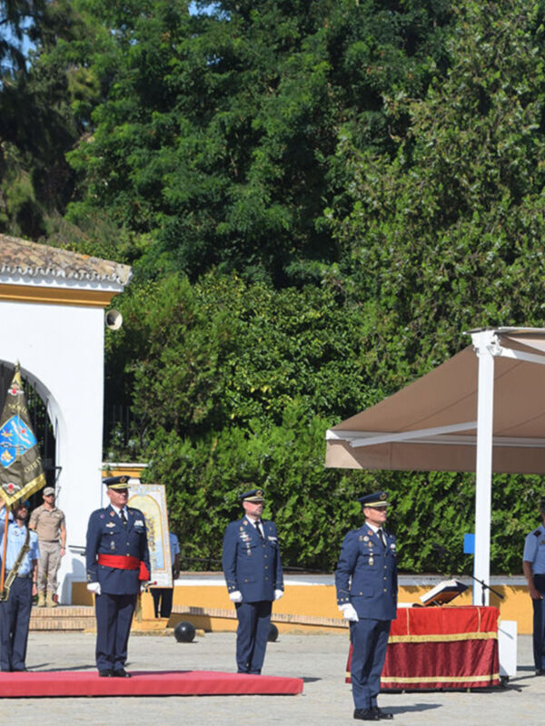 Formal ceremony with military personnel in uniform, standing in a line, and a flag being presented.