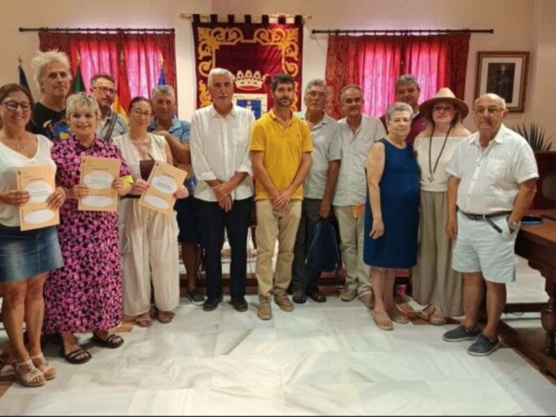 Grupo de personas posando con certificados en un salón con decoración formal.