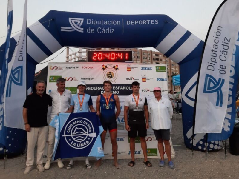 Carrera de atletismo con ganadores en el podio, frente a un escenario con logotipos de Diputación de Cádiz y Toyota.