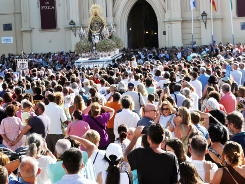 Una multitud de personas congregadas frente a una iglesia, con un altar central adornado y banderas ondeando en el fondo.