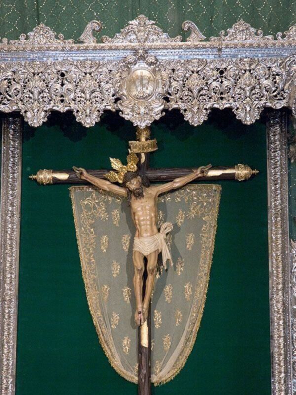 Crucifijo enmarcado con detalles dorados y un fondo verde.