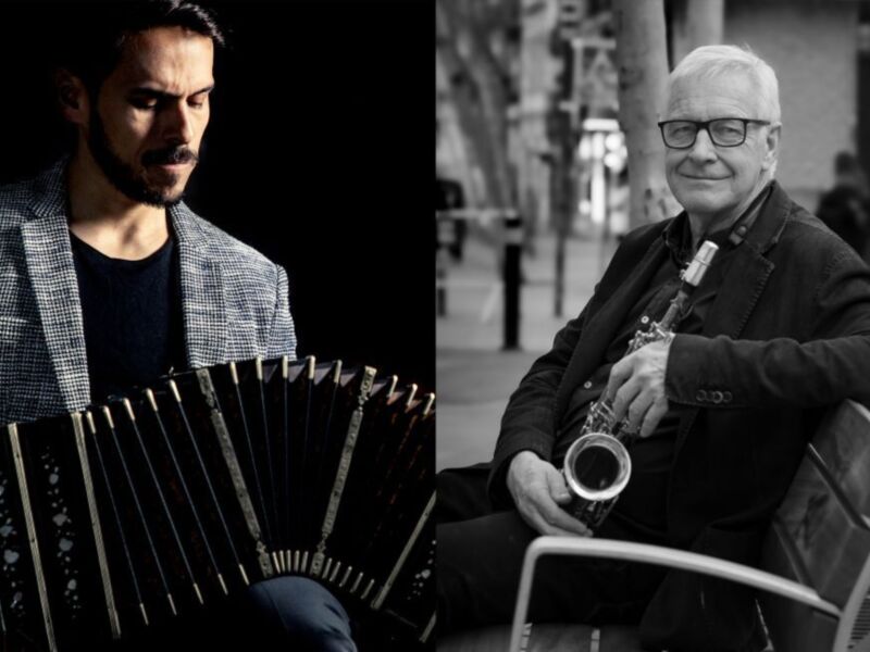 Dos músicos en blanco y negro: uno con un acordeón y otro tocando saxofón. Ambos están sentados en una calle con edificios al fondo.