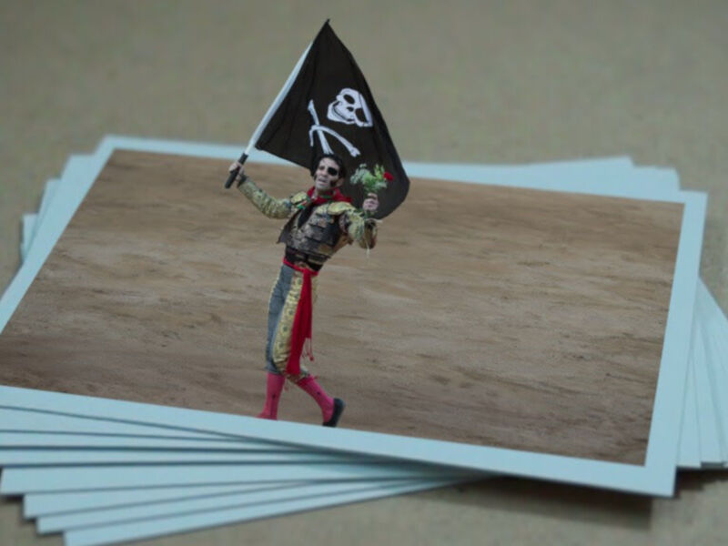 Una imagen de un torero con una bandera pirata en la mano, sobre un fondo de madera.