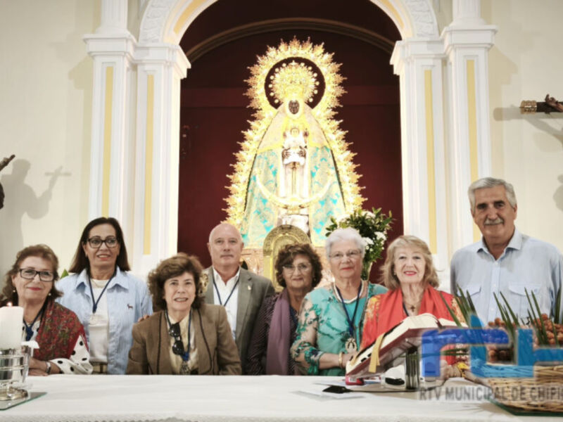 Una imagen de una reunión religiosa en un templo, con una Virgen María en el centro y varias personas sentadas a su alrededor.