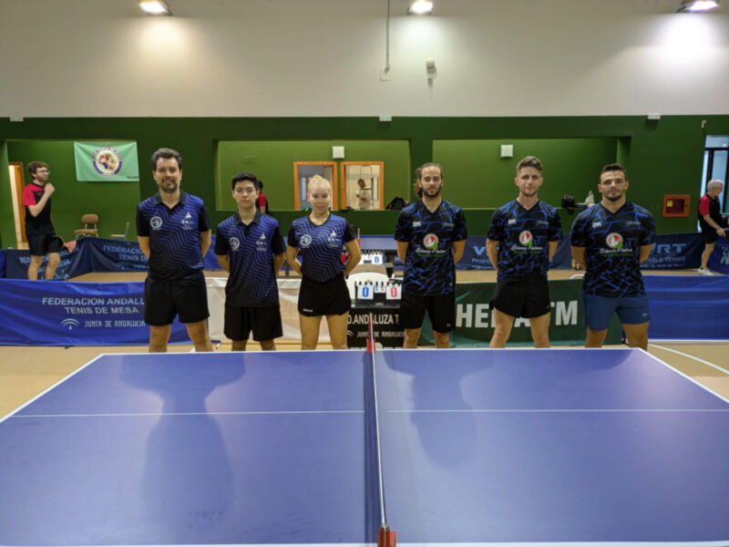 Equipo de tenis de mesa posando en el campo con banderas y logotipos visibles.