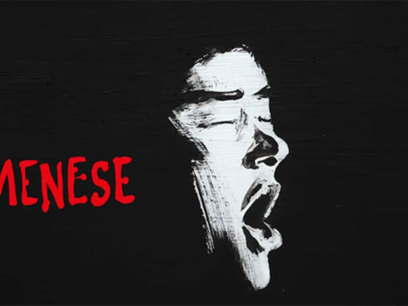 Una ilustración de un rostro humano con una expresión de dolor o angustia, dibujado en blanco sobre un fondo negro. El texto "MENENSE" está escrito en rojo en la parte inferior de la imagen.