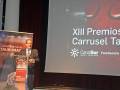 El XIII Premios Carrusel Taurino se celebró en el Teatro de la Maestranza, con un hombre en traje y corbata haciendo uso del micrófono frente a una pantalla que muestra el logo de Canal Sur y la frase "XIII Premios Carrusel Taurino".