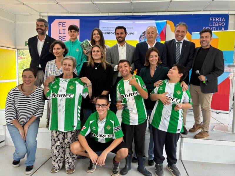 Grupo de personas posando con camisetas del Real Betis Balompié en una feria.