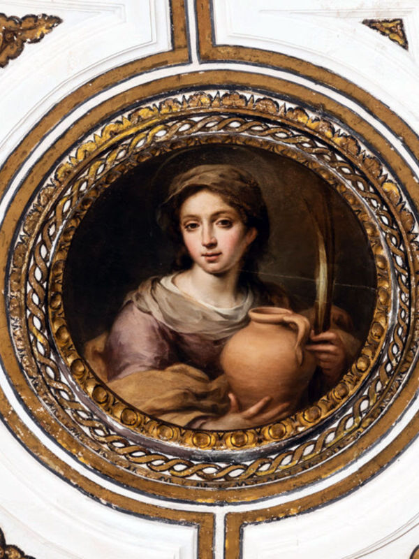 Un retrato de una mujer pintado en un marco dorado y decorativo, representando a una santa. La figura está vestida con un manto y sostiene un objeto que parece ser una lámpara. El estilo artístico sugiere influencias barrocas o renacentistas, típicas de la época del Barroco.