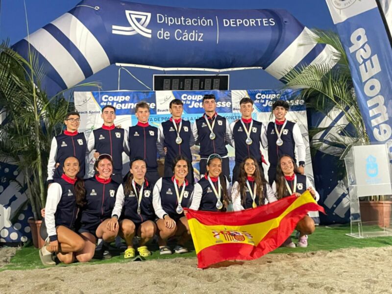 Equipo de fútbol celebrando con medallas y bandera española, en un escenario deportivo con banners de la Diputación de Cádiz y la Copa del Rey.