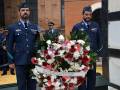 Guardias de honor en uniforme militar con una corona floral frente a un edificio histórico.