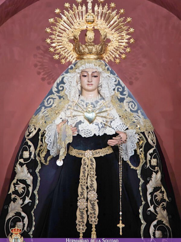 Imagen de la Virgen María vestida con trajes tradicionales en un entorno religioso.