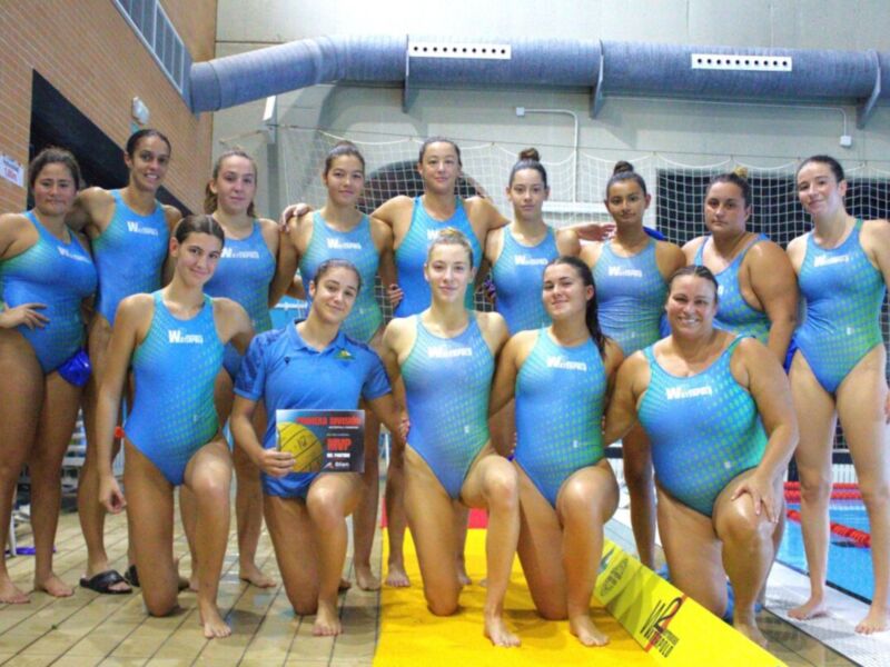 Equipo femenino de natación posando en la piscina.